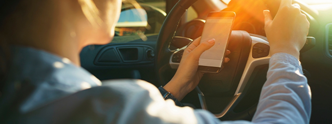 mujer manejando con celular en mano