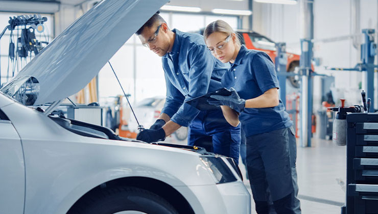 Two auto mechanics looking under the hood of a vehicle