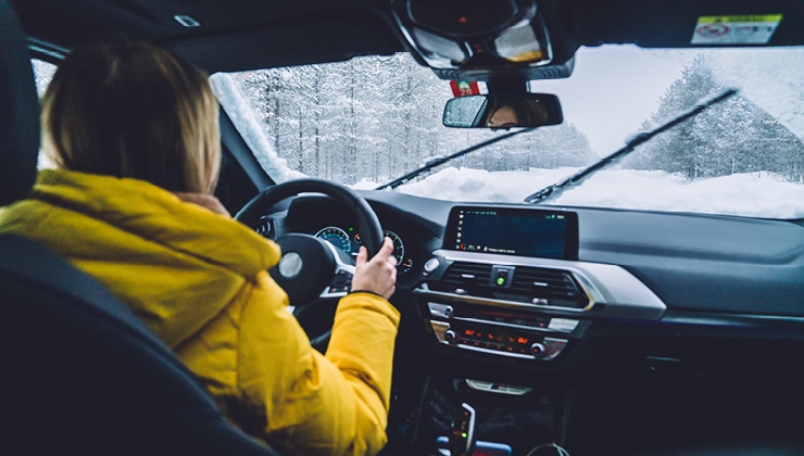 woman driving in snowstorm checking safety features