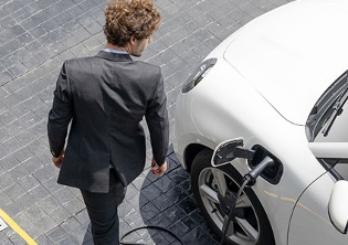 hombre a lado de coche eléctrico cargándose